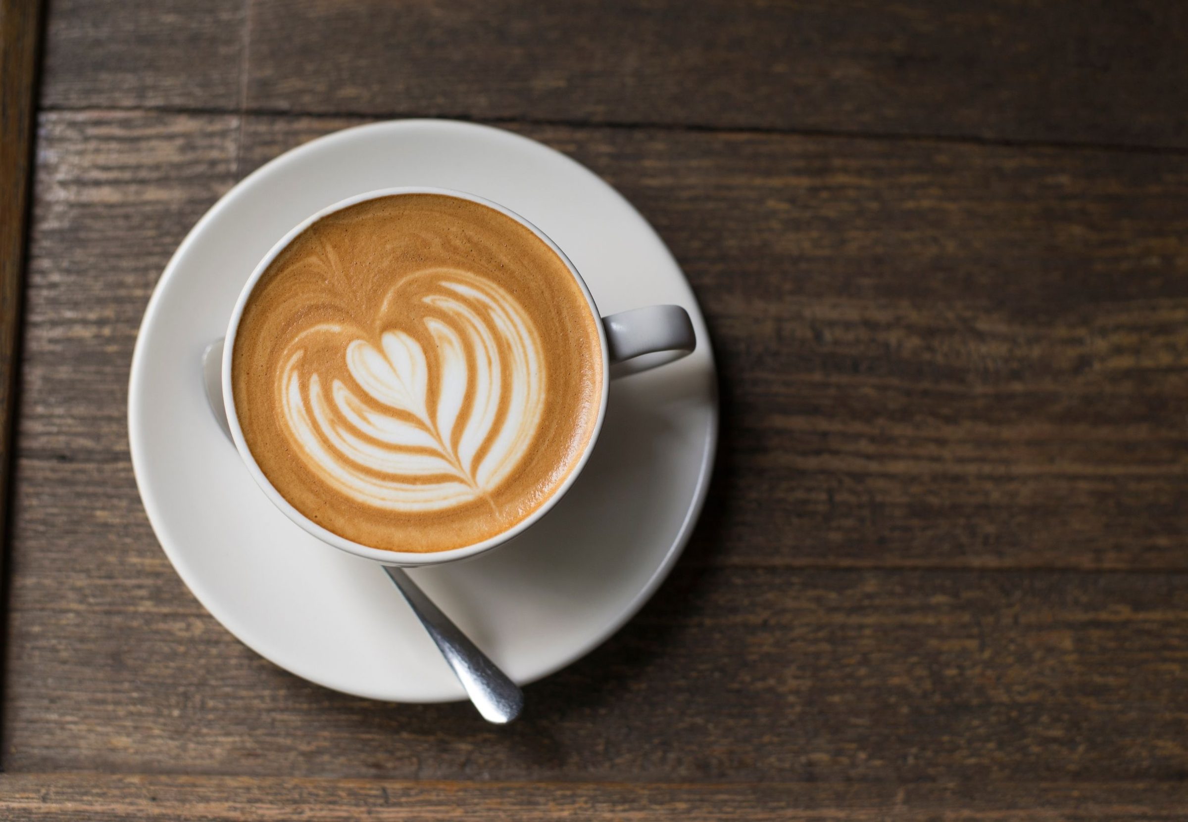 A flat white on a wooden caf&eacute; table