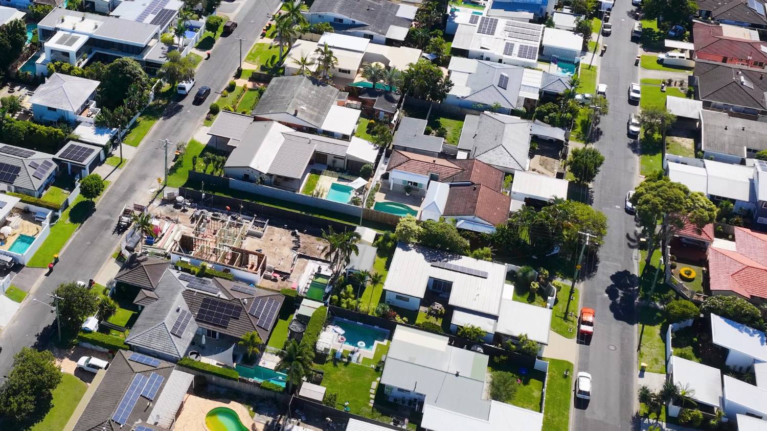 An Australian suburban street of low-set houses with gardens and parked cars