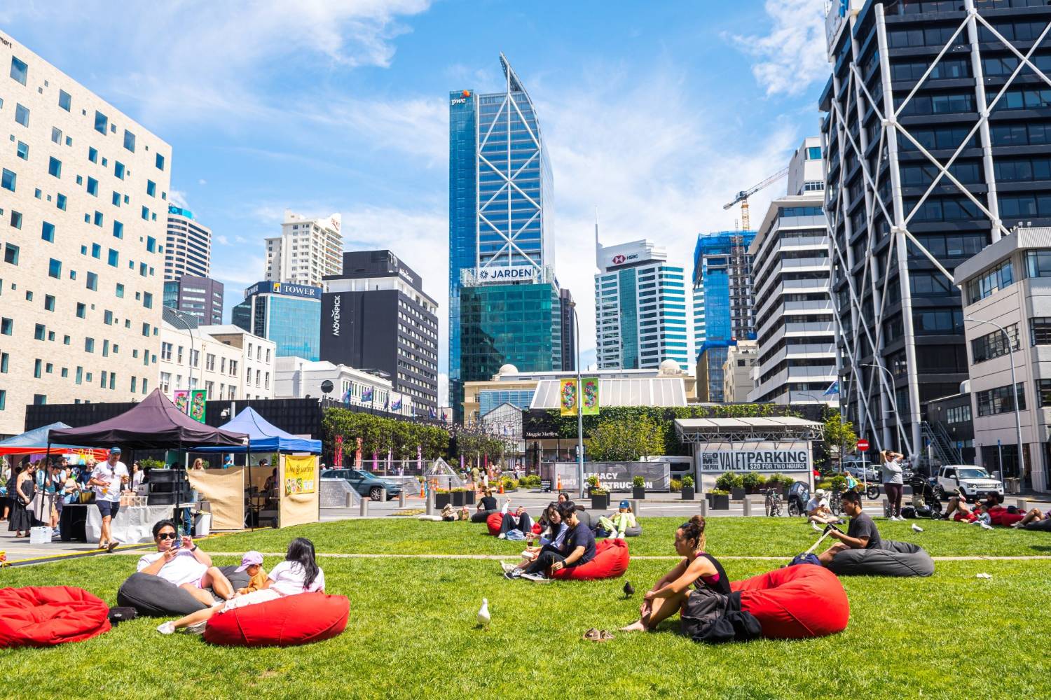 People relaxing on the lawn of a downtown Auckland park with the city skyline behind