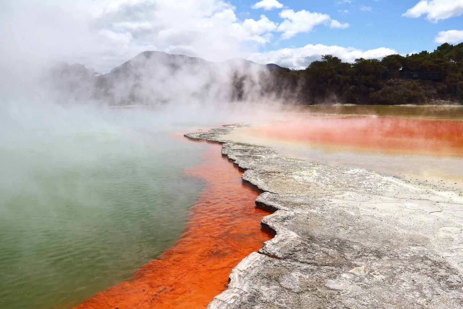 A vivid turquoise geothermal pool ringed by orange mineral deposits