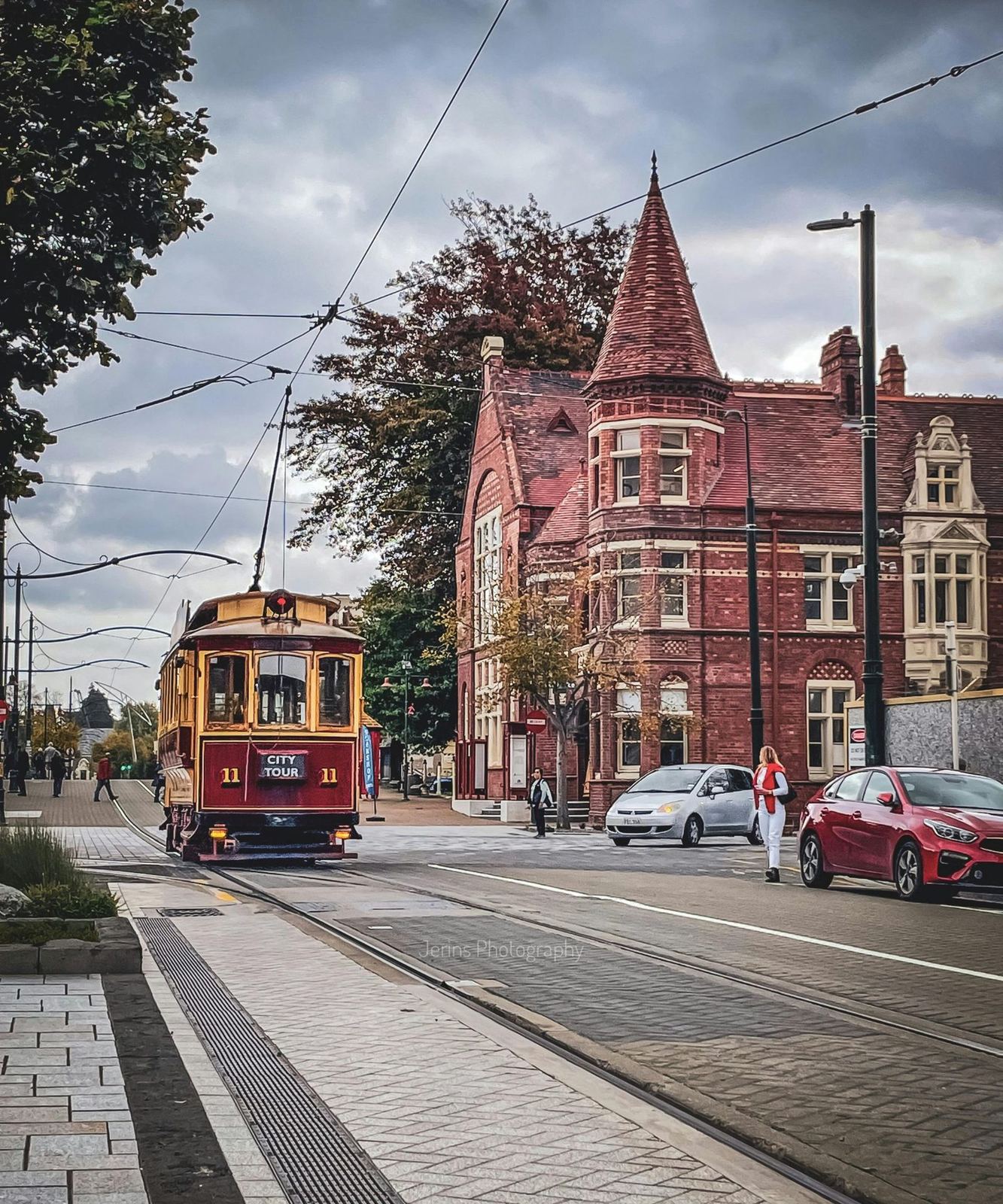 A heritage tram passing Gothic Revival buildings in central Christchurch