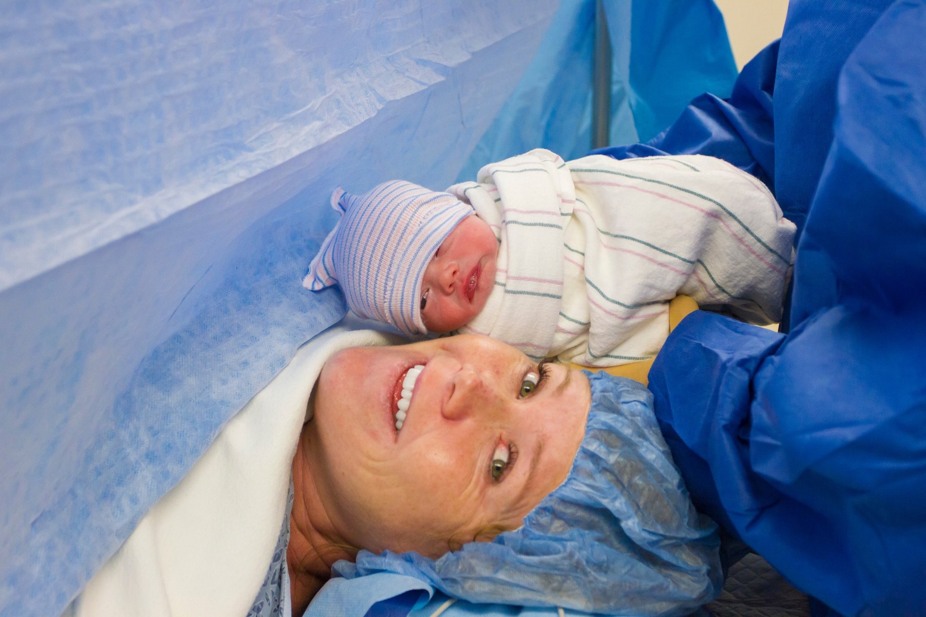 A mother and her newborn beside each other in theatre after a caesarean birth