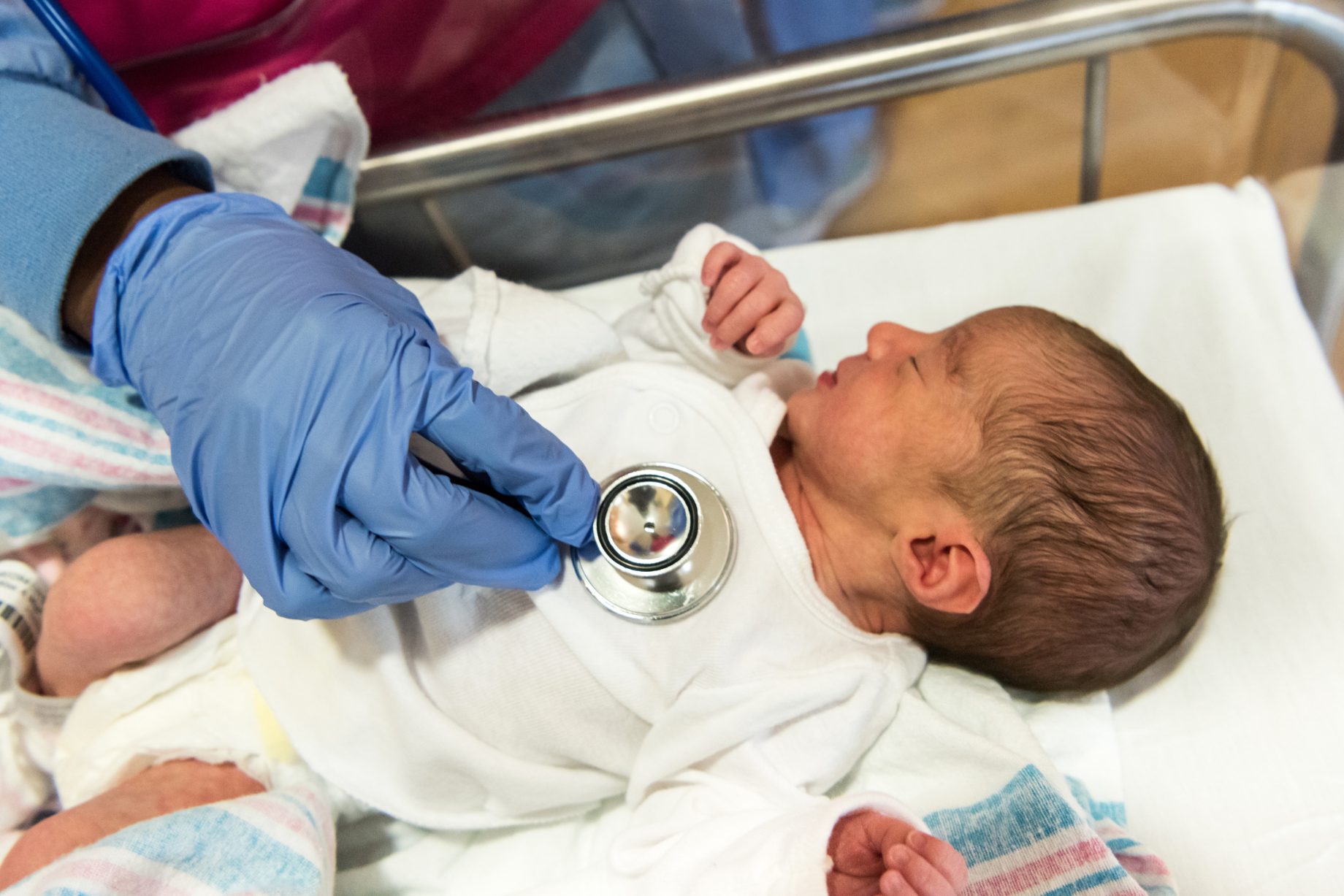 A midwife carrying out a newborn check, weighing a baby on a set of scales