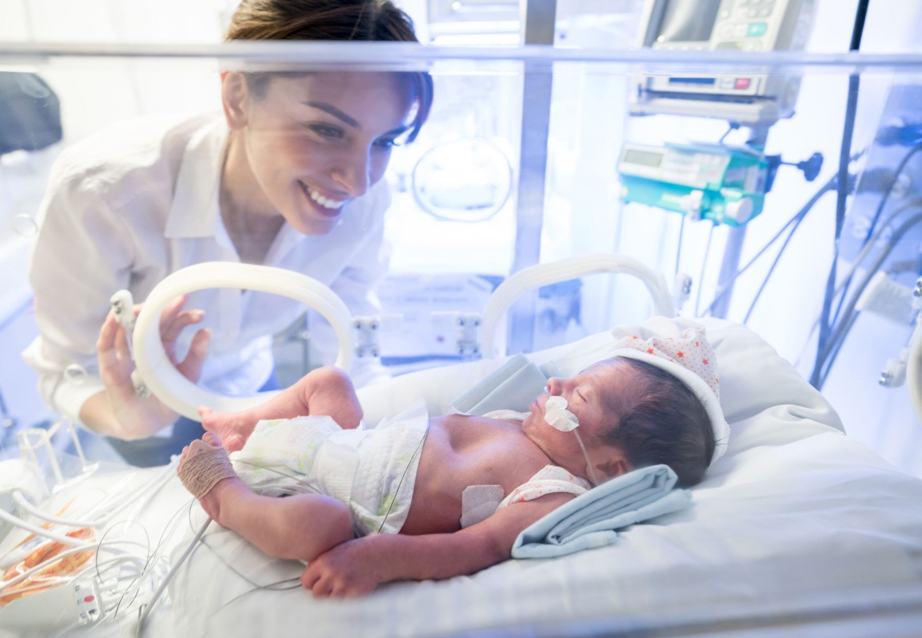 A nurse beside a baby in a neonatal incubator