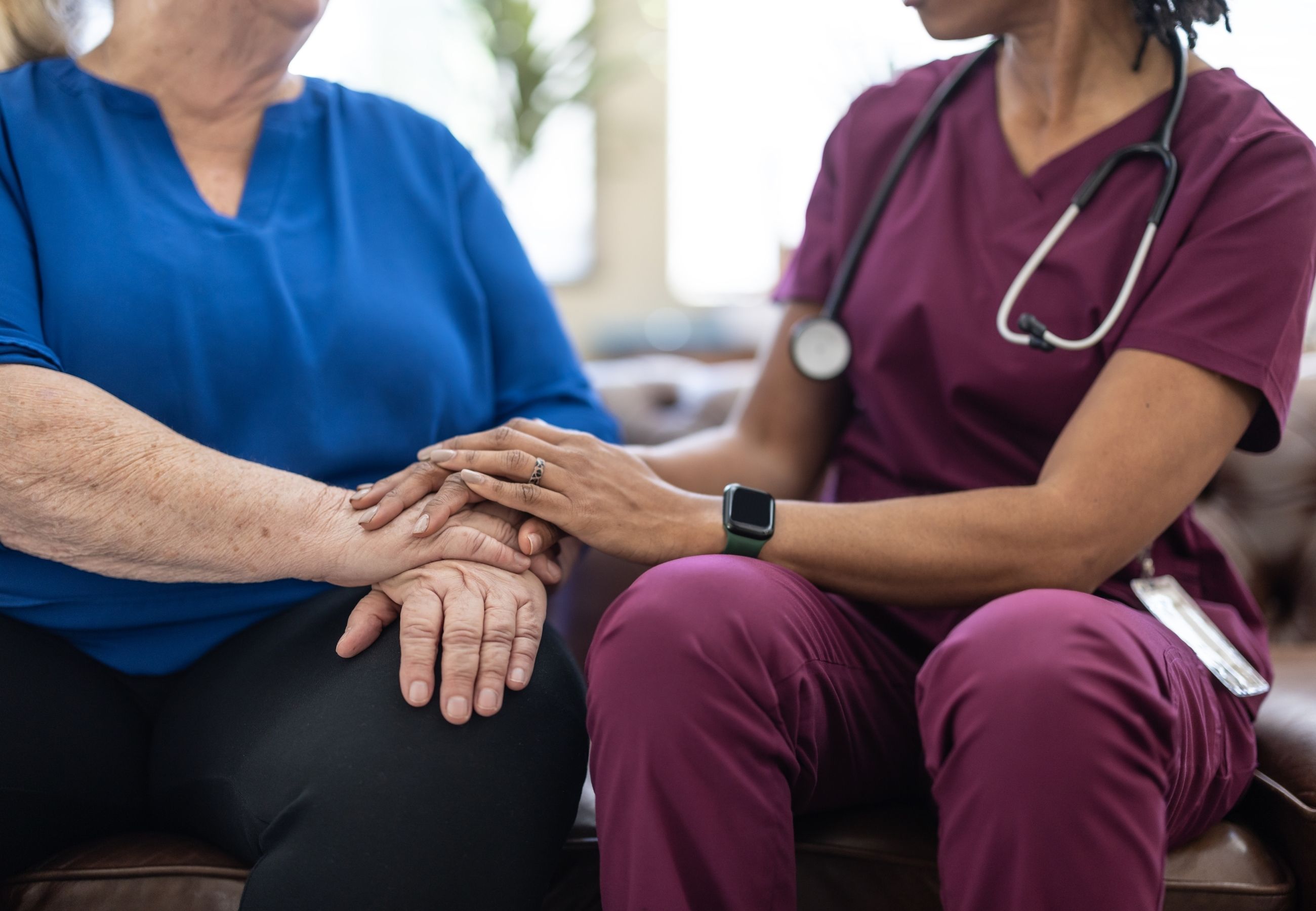 A nurse holding a patient&rsquo;s hand at the bedside