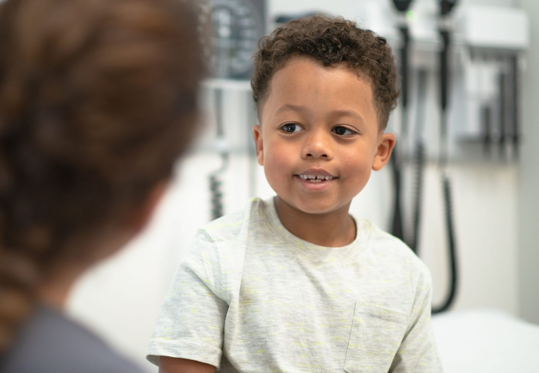 A young boy smiling at his paediatrician during a clinic appointment