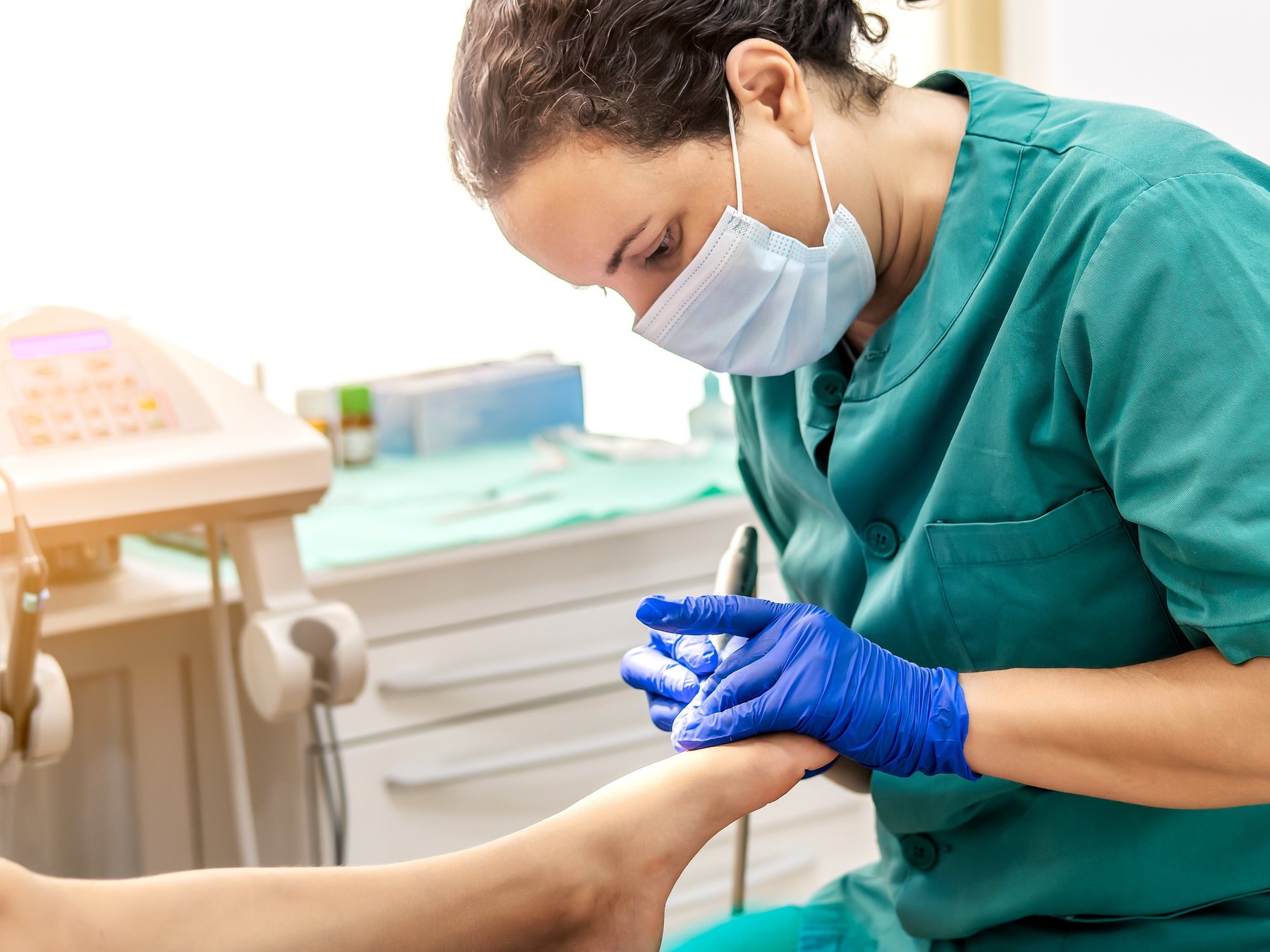 A podiatrist treating a patient&rsquo;s foot in a clinic
