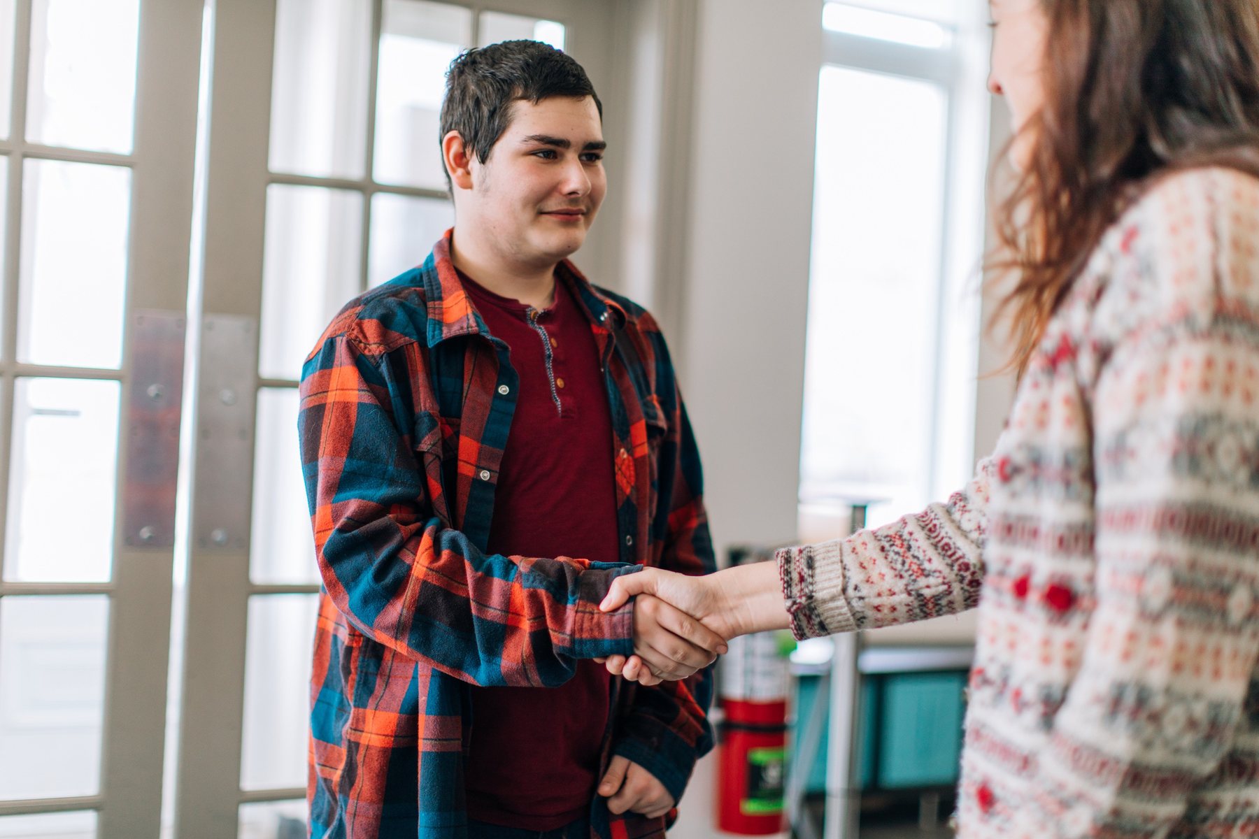 A social worker greeting a young man at the door of a community service