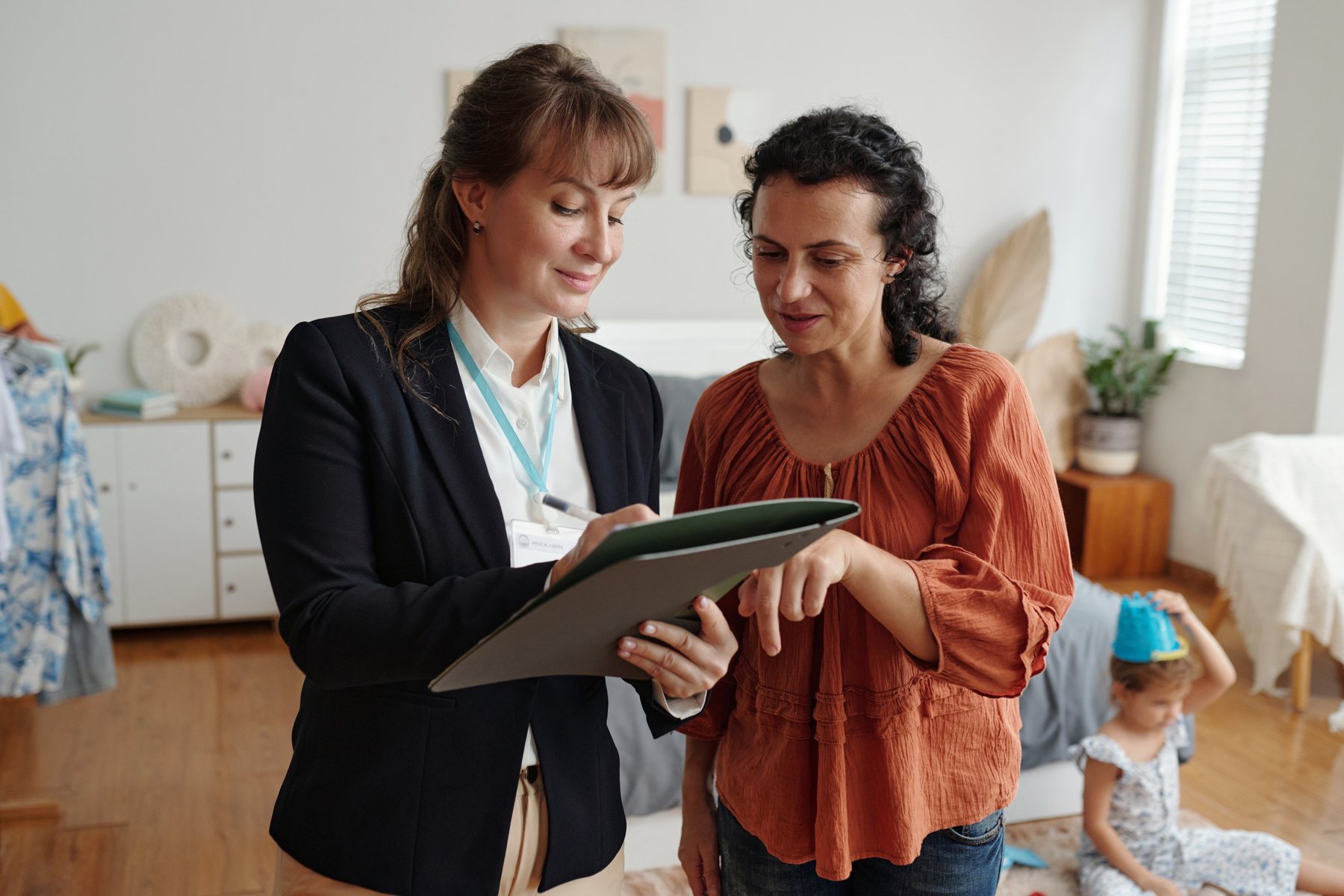 A social worker going through paperwork with a mother at home