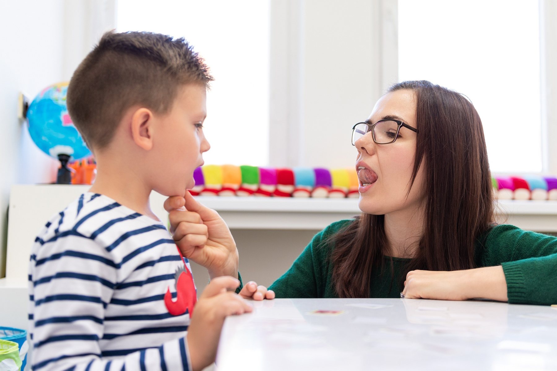 A speech-language therapist modelling a sound with a young boy