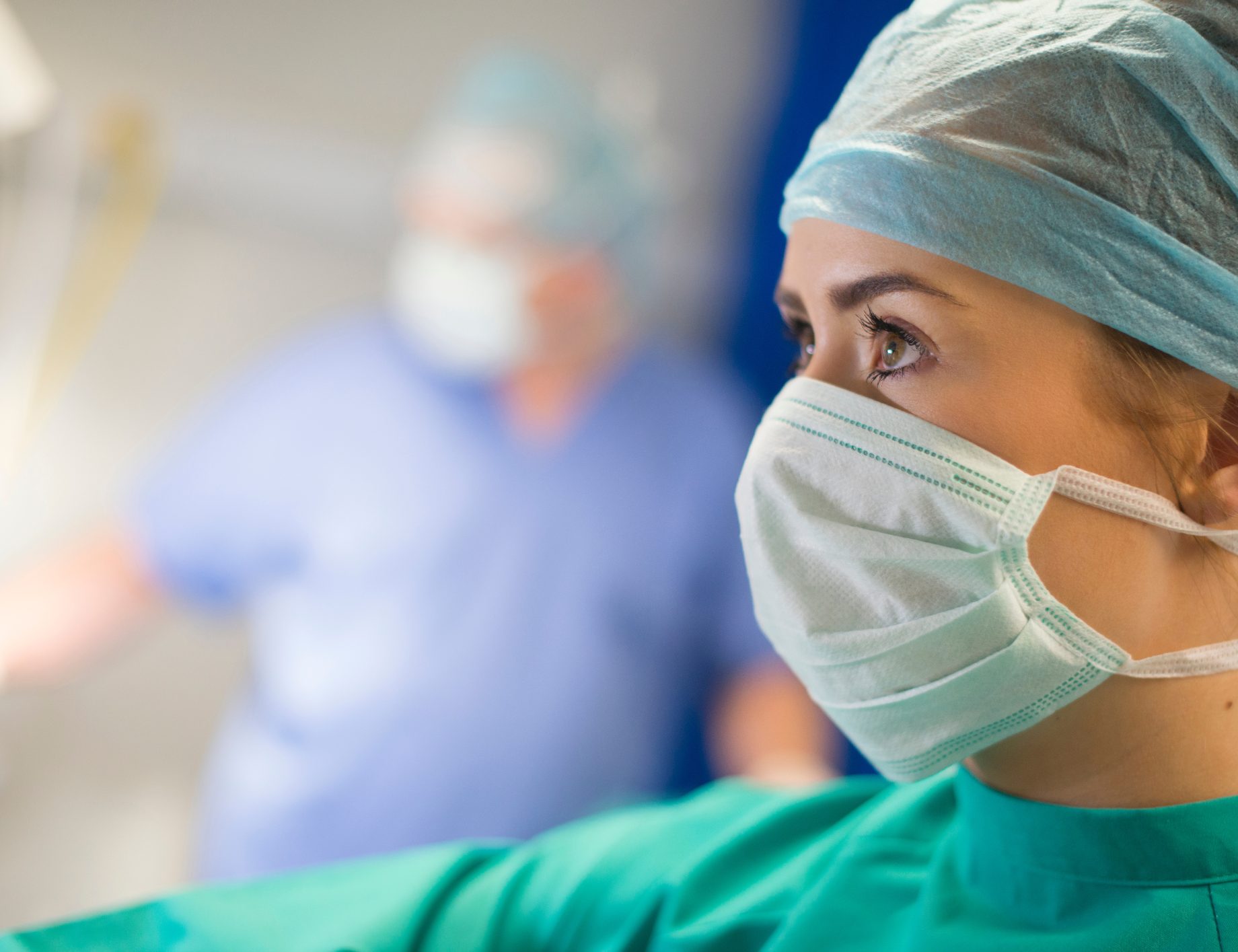An anaesthetist in cap and mask in an operating theatre