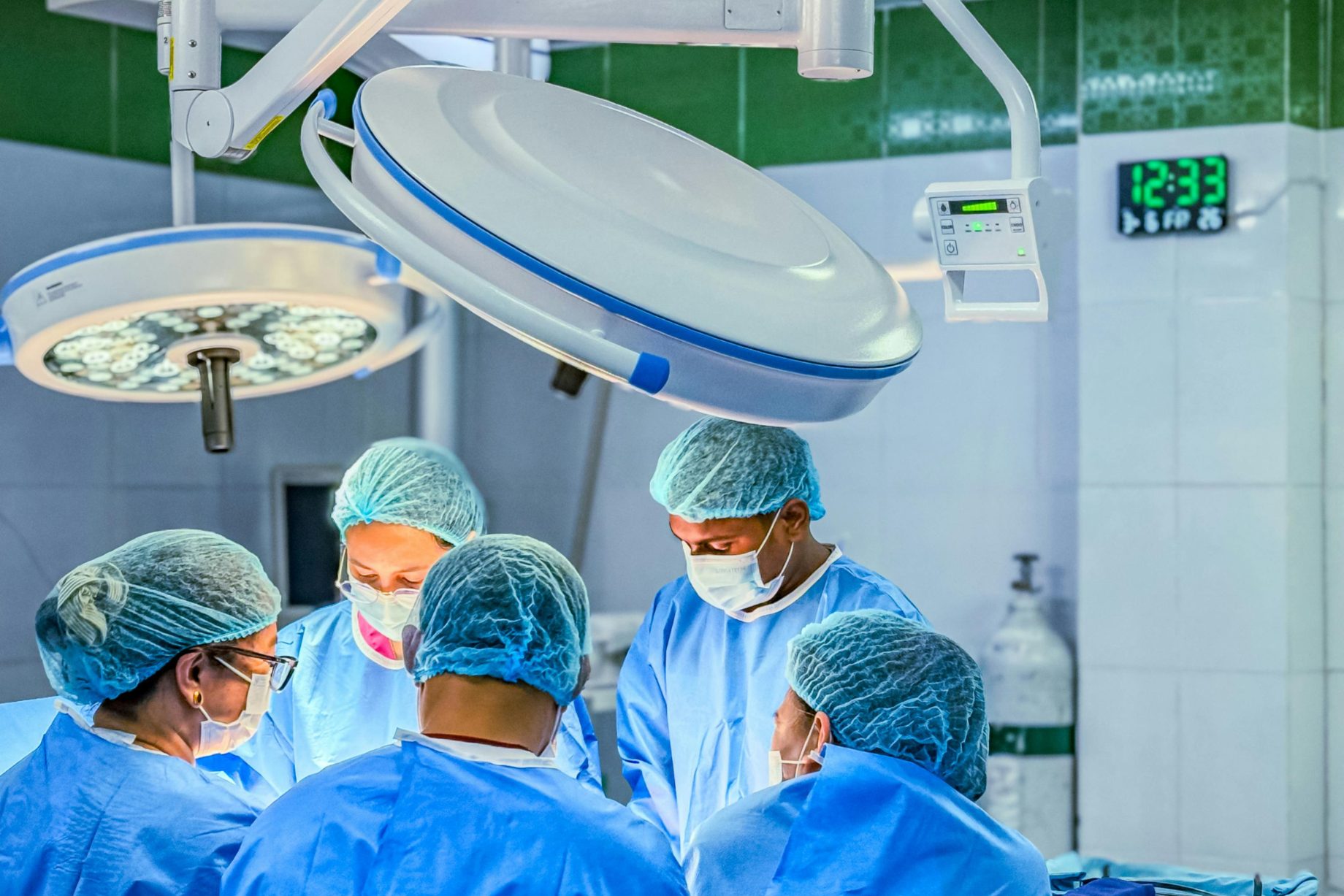 A theatre team in caps and masks gathered around the operating table