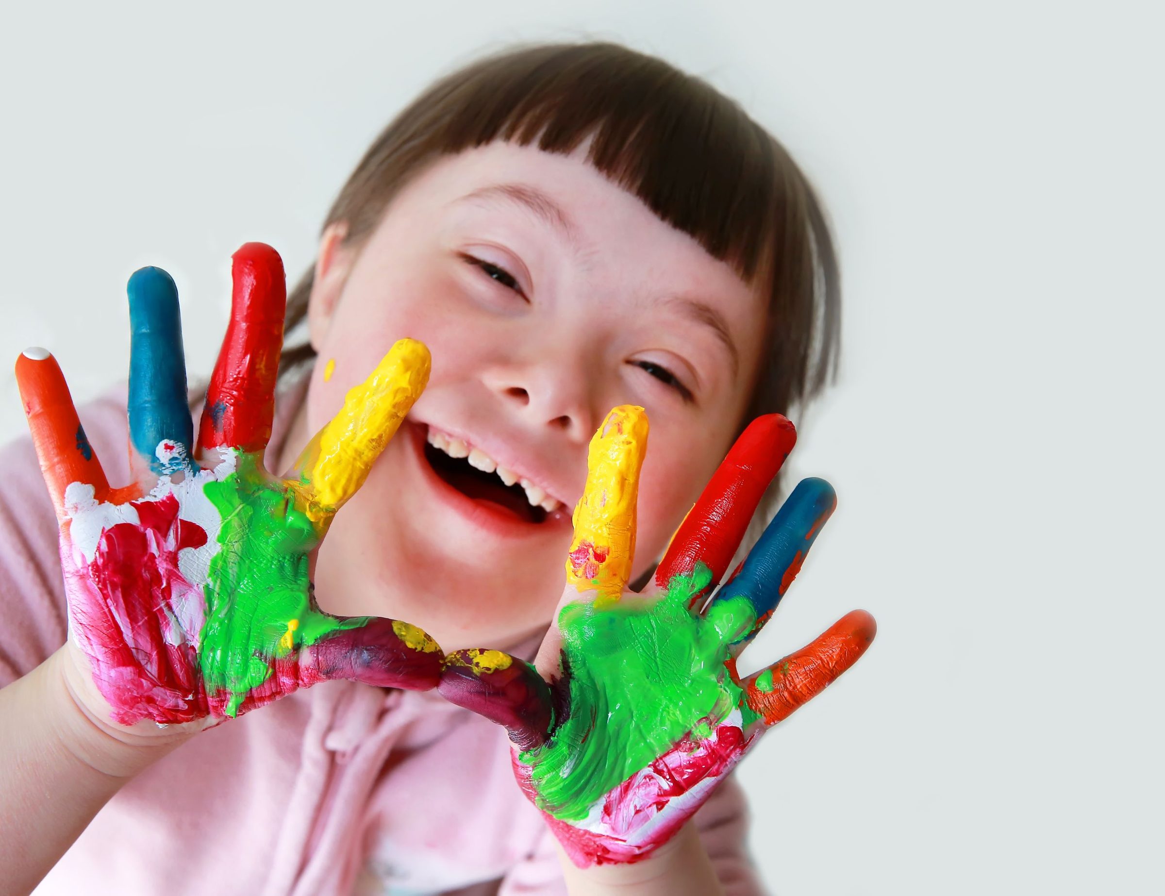 A laughing child holding up paint-covered hands