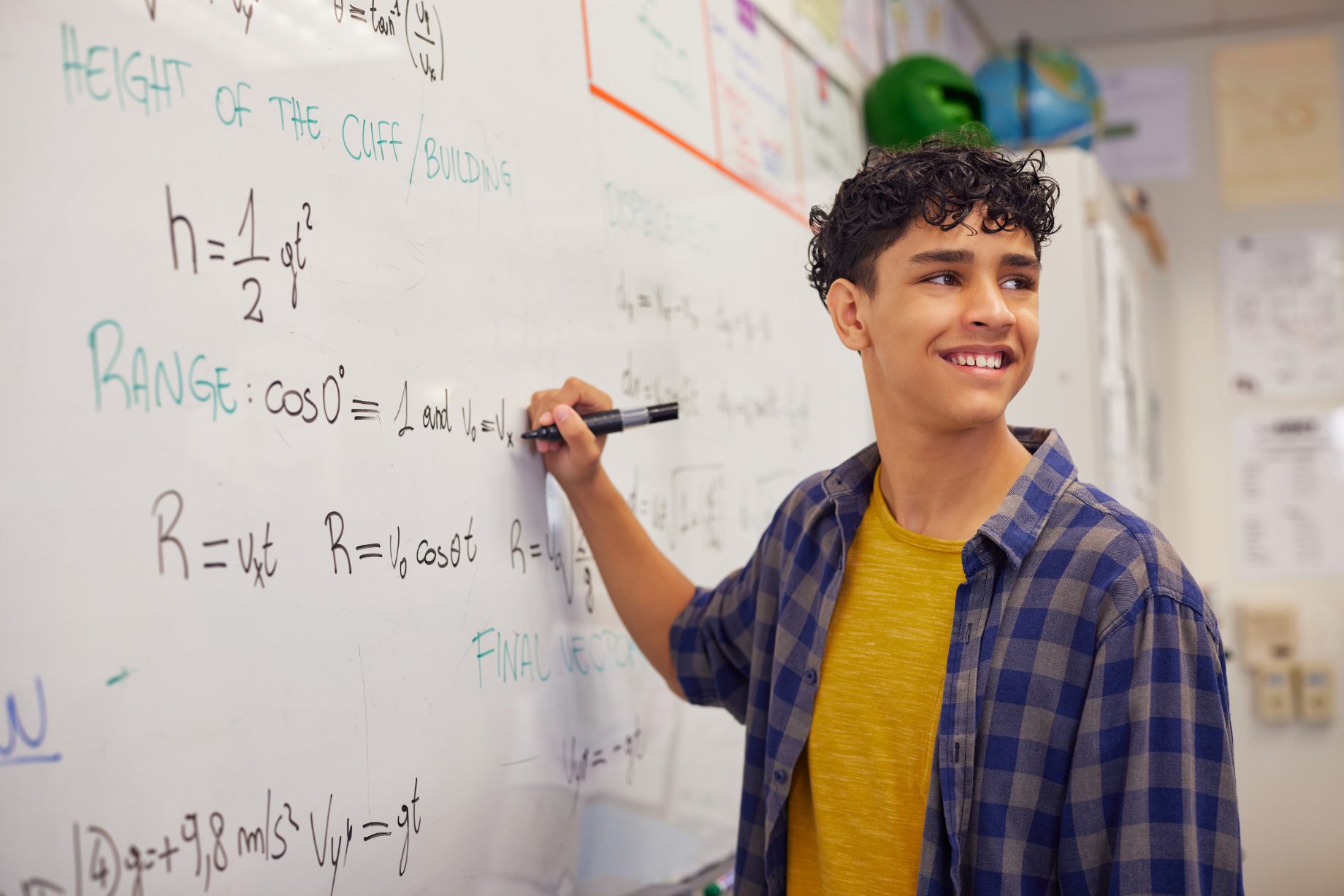 A senior secondary student working through a physics problem at a whiteboard