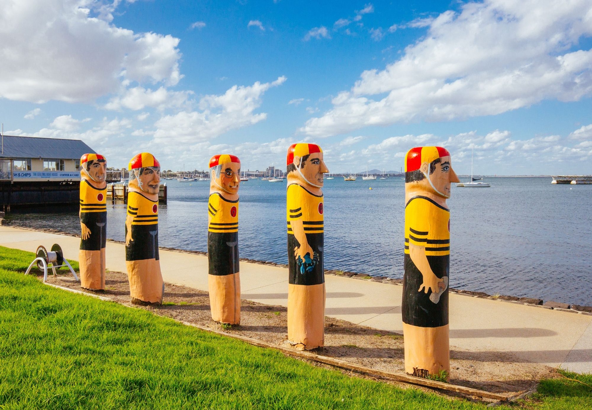 Painted bollard figures along the Geelong waterfront, the bay behind
