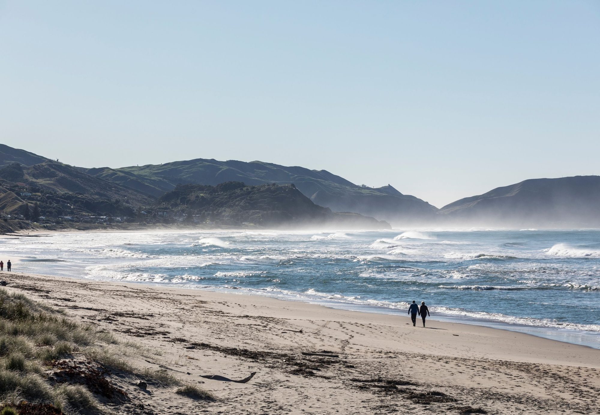 Waves rolling in on Wainui Beach, Gisborne, with hills behind