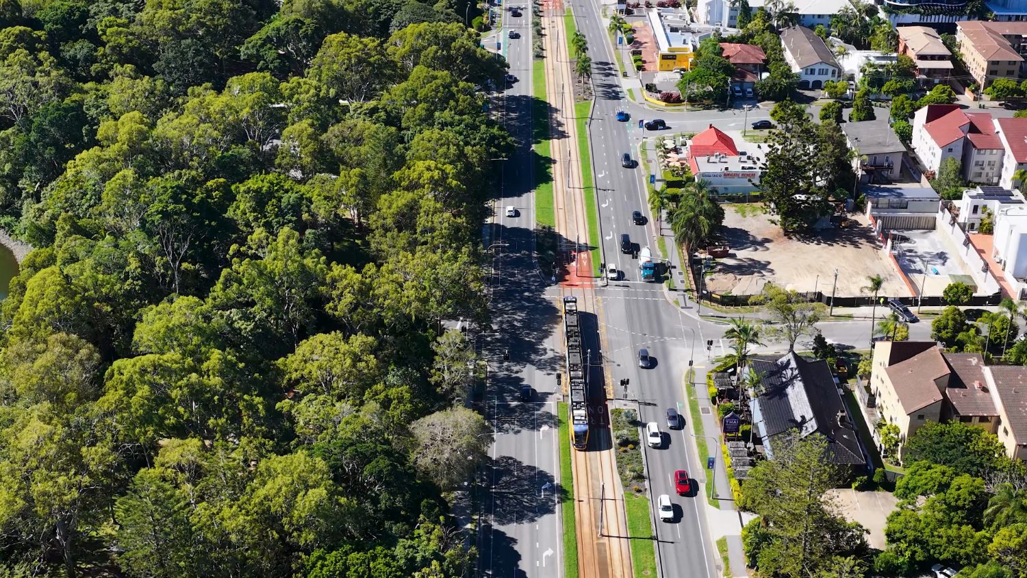 The G:link light rail running along a tree-lined road on the Gold Coast