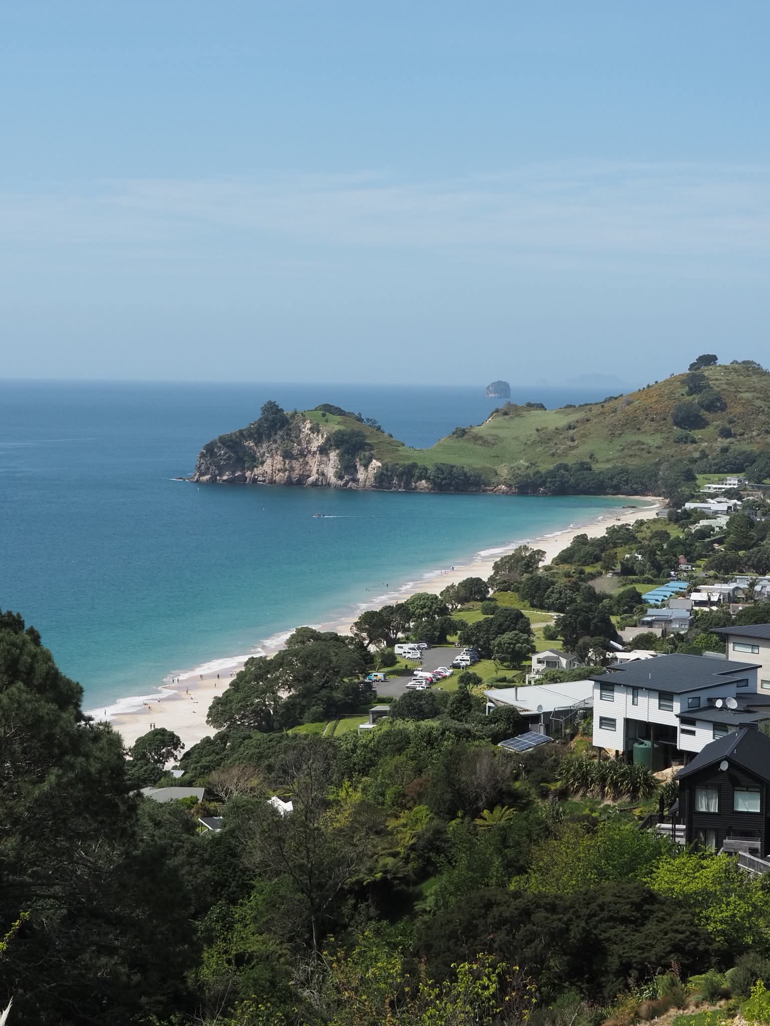 A white-sand bay curving towards a green headland in Northland, photographed by Emad