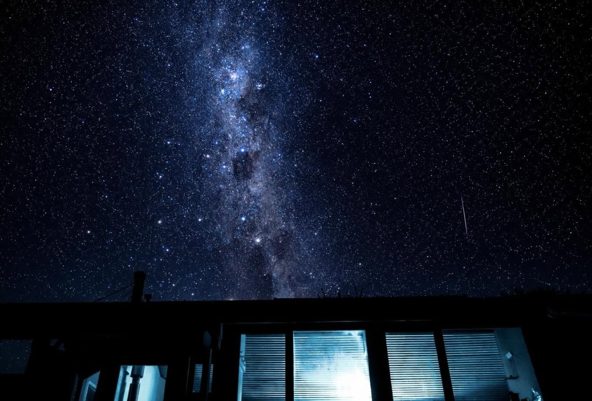 The Milky Way and a sky full of stars above a backcountry hut, its windows lit from inside
