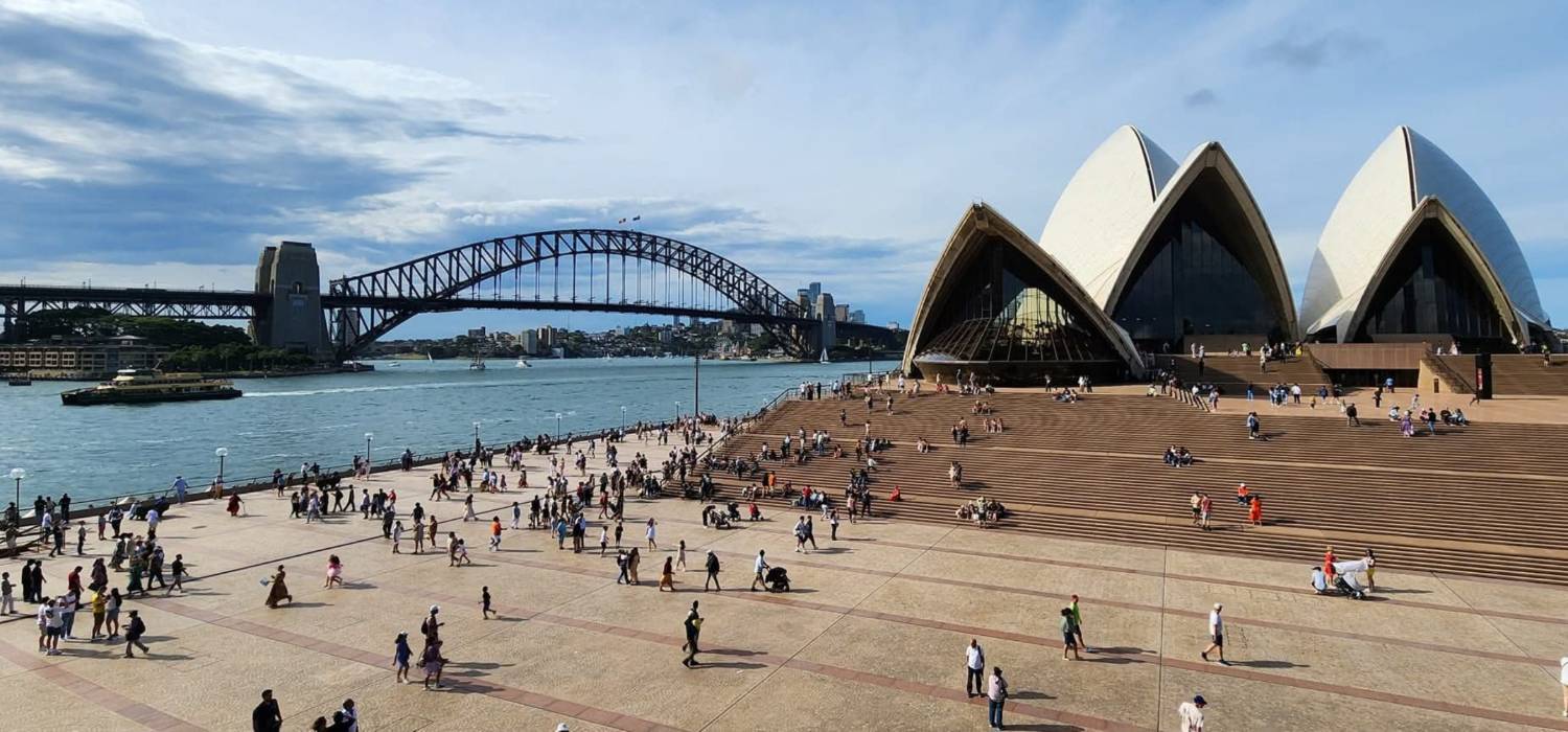 The Opera House forecourt and the Harbour Bridge on a busy afternoon