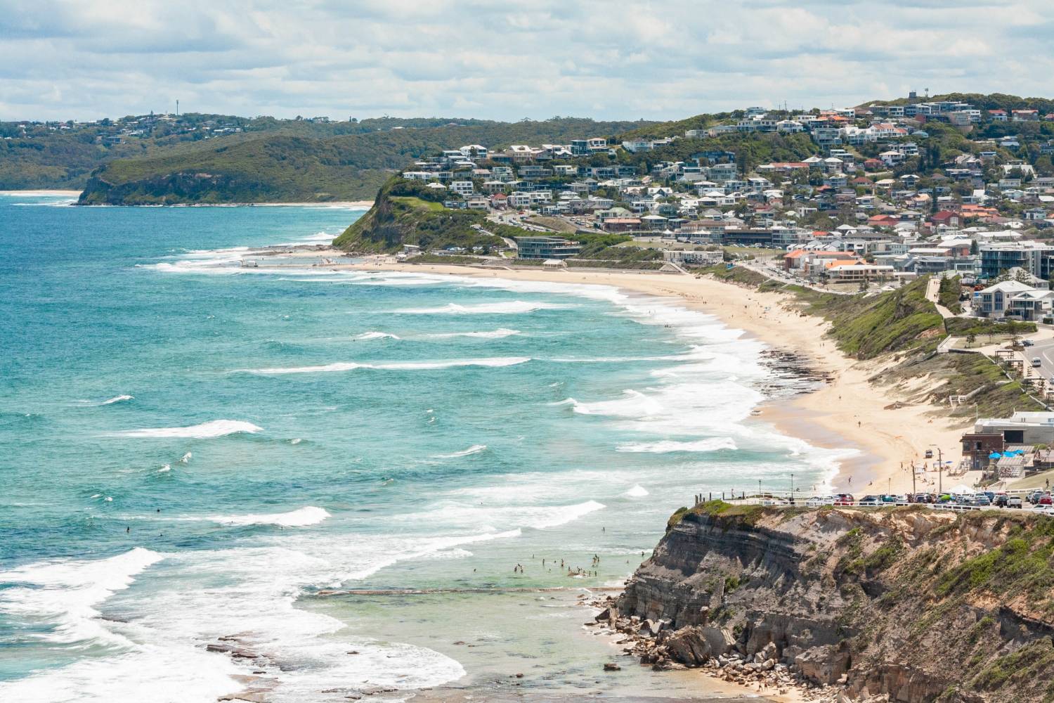 Newcastle&rsquo;s coastline curving past the headland, the suburbs behind