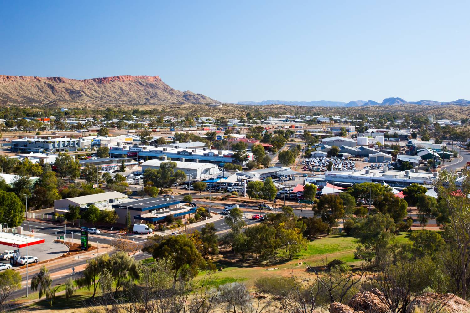 Alice Springs in Central Australia, low buildings and wide streets spread out below the red escarpment of the MacDonnell Ranges.