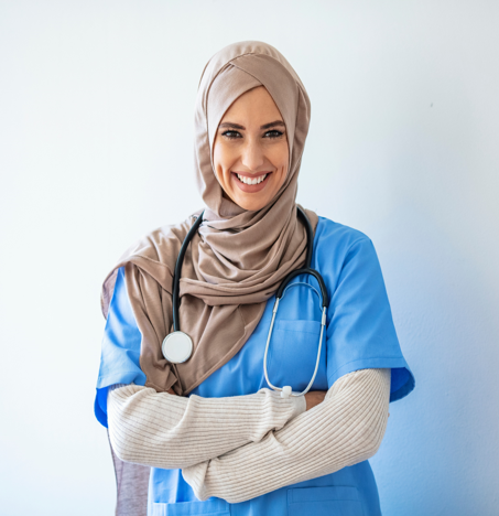 A smiling nurse in scrubs with a stethoscope, arms folded