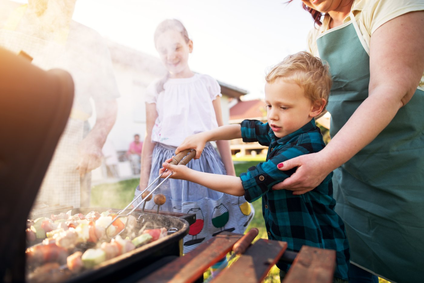 Friends and family gathered around a barbecue in a back garden