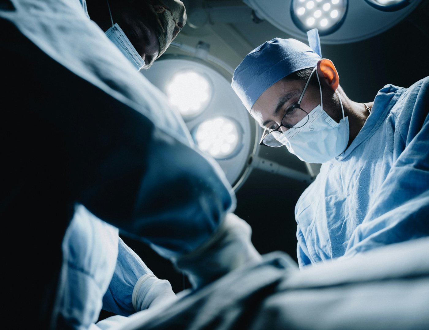 Two clinicians working under the lights in an operating theatre