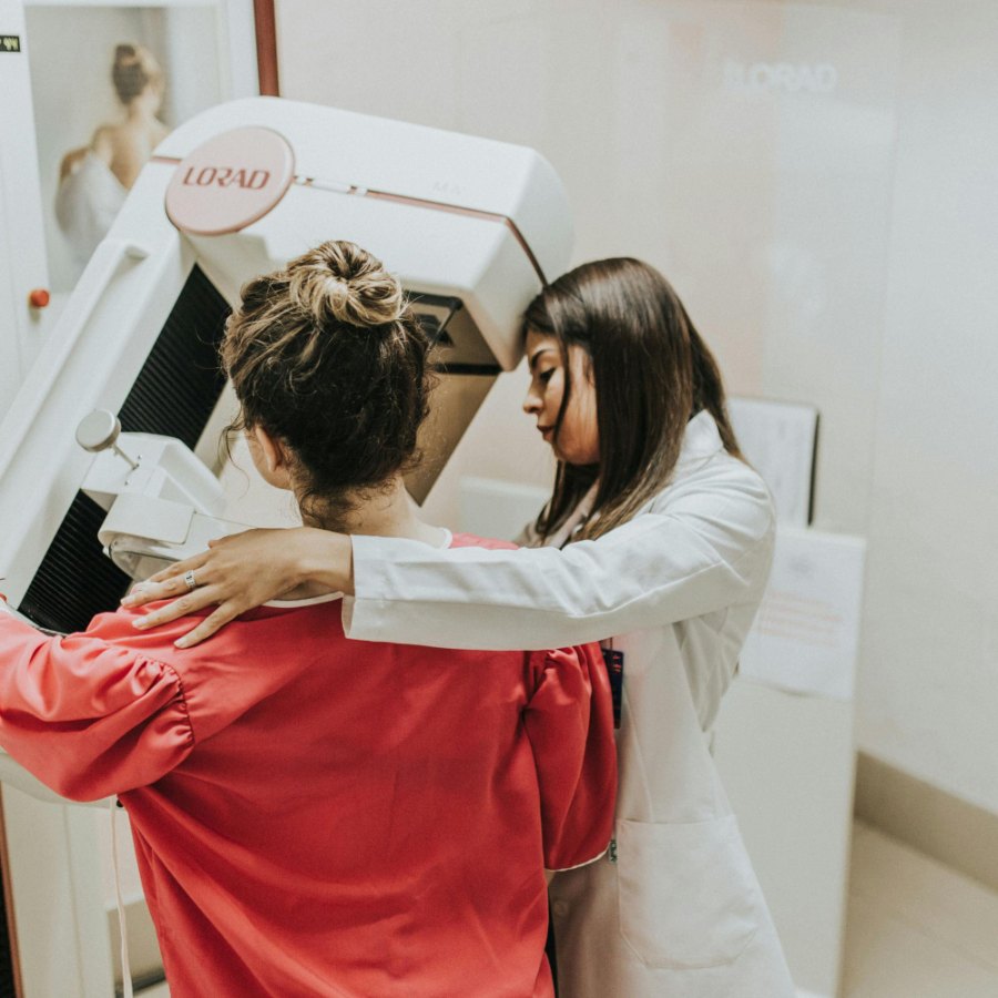 Two imaging staff positioning a patient at a scanner