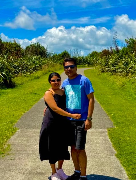 Neethu and her husband on a sunny coastal path lined with flax
