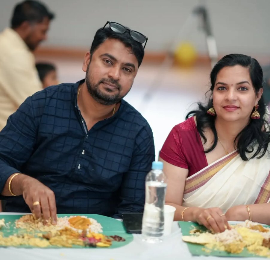 Rezon and his wife in traditional Kerala dress sharing an Onam sadya served on banana leaves