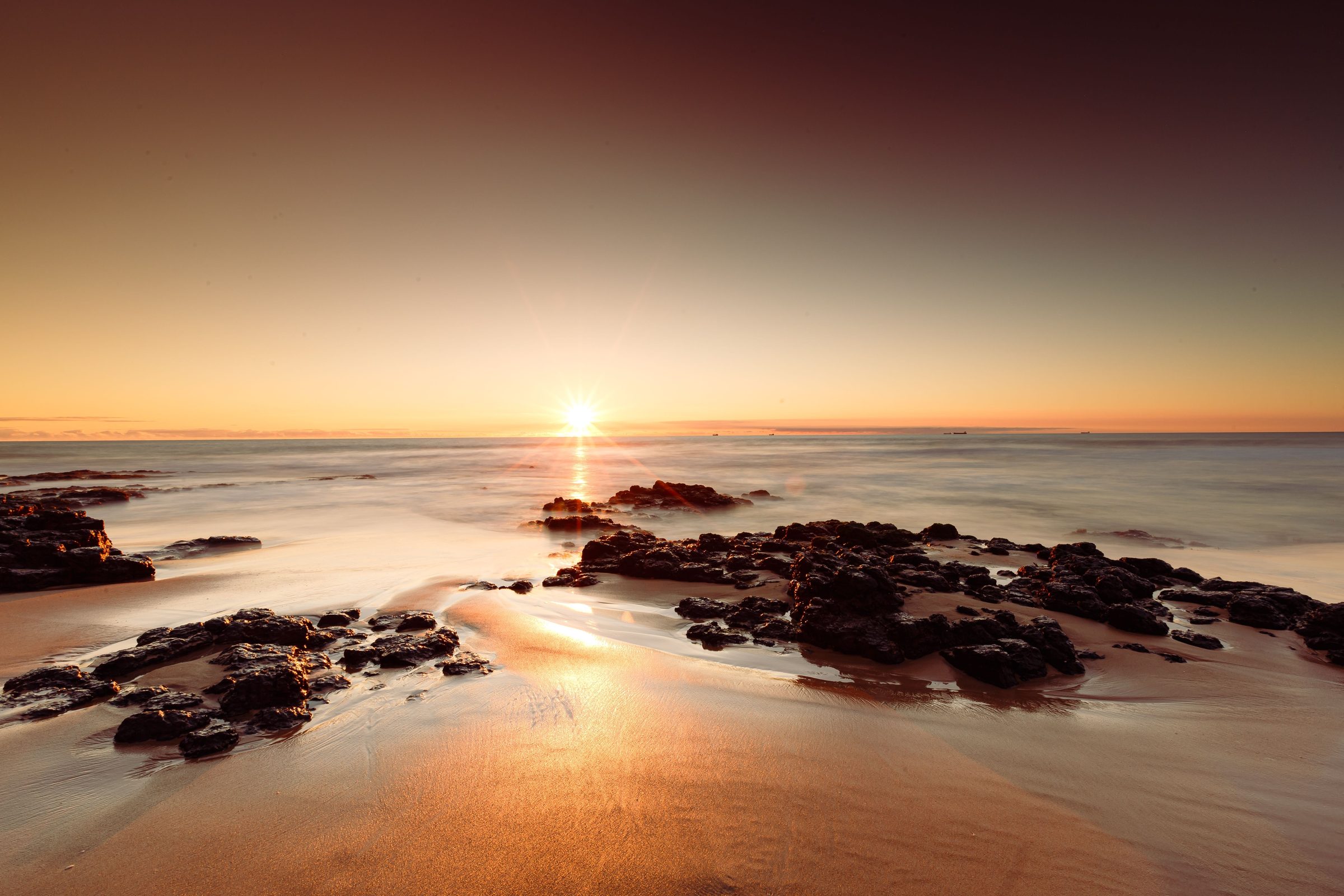 Bunbury beach at sunset, a long empty shoreline under a pink sky