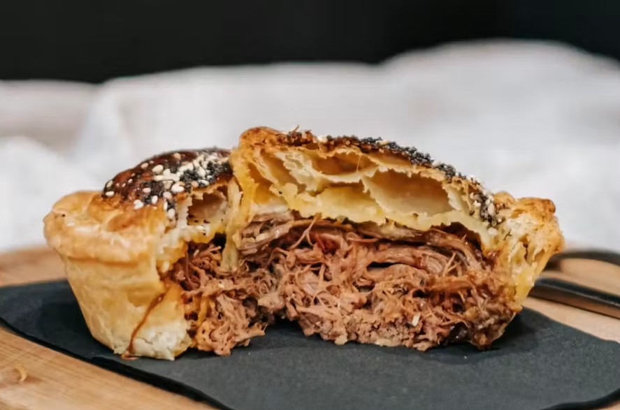 A pulled-beef pie with flaky seeded pastry, cut open