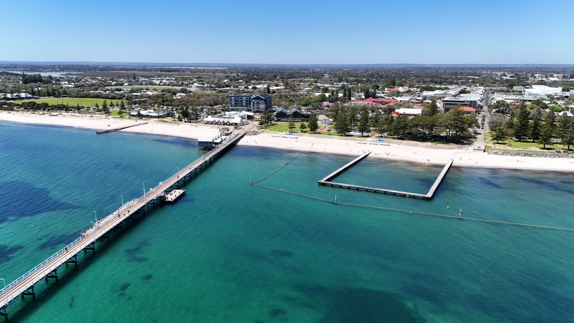 The long timber jetty at Busselton reaching out over turquoise water, with the town behind